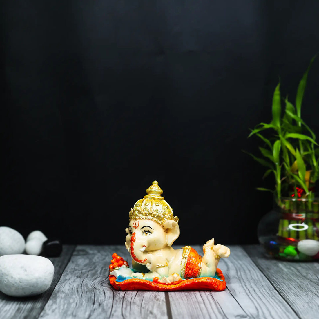 Aurance handcrafted resin Bal Ganesha figurine reading the Ramayana, featuring gold and orange accents on a wooden base.