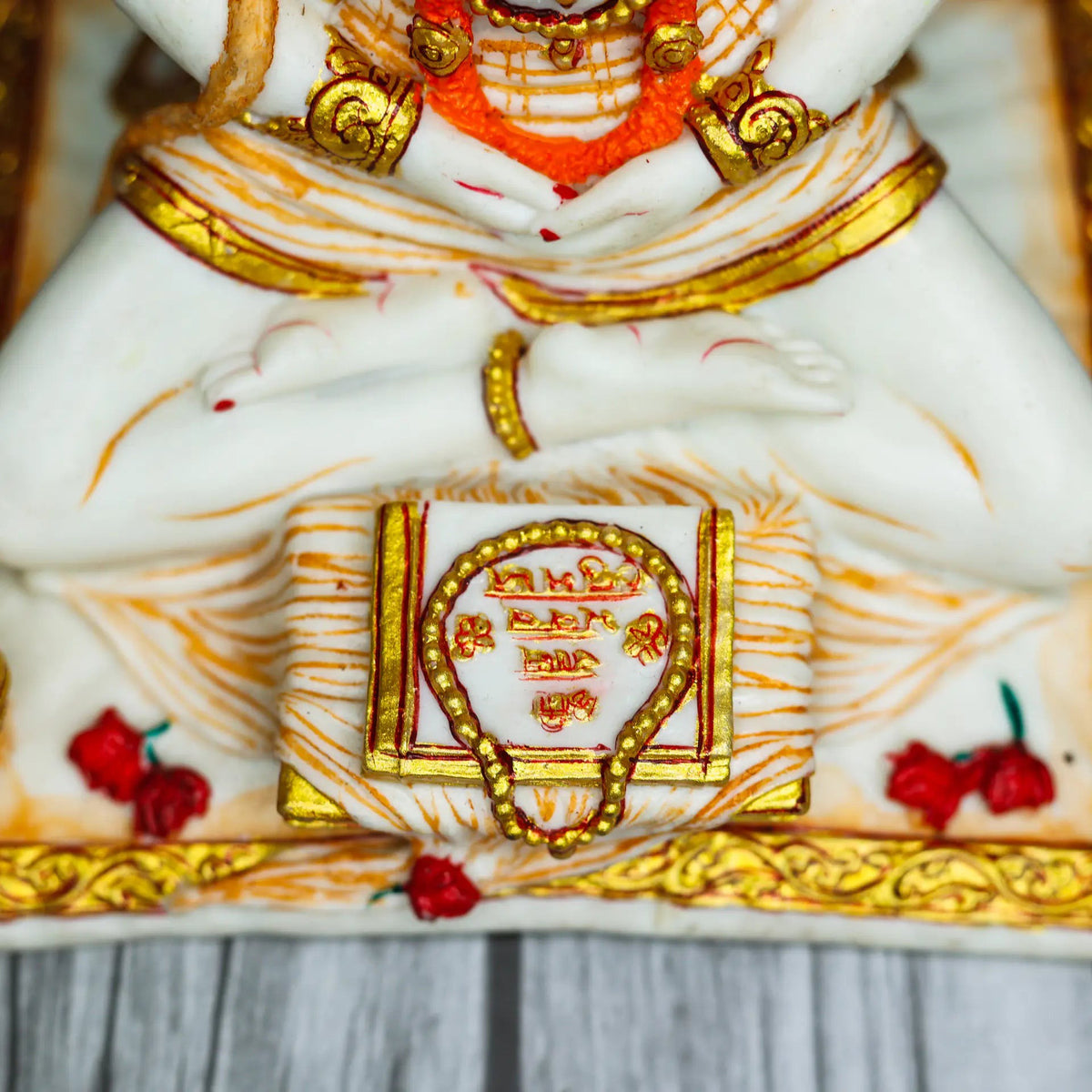 Aurance Lord Hanuman sitting statue in a meditative pose, reading a book with gold and red accents and a gada nearby.
