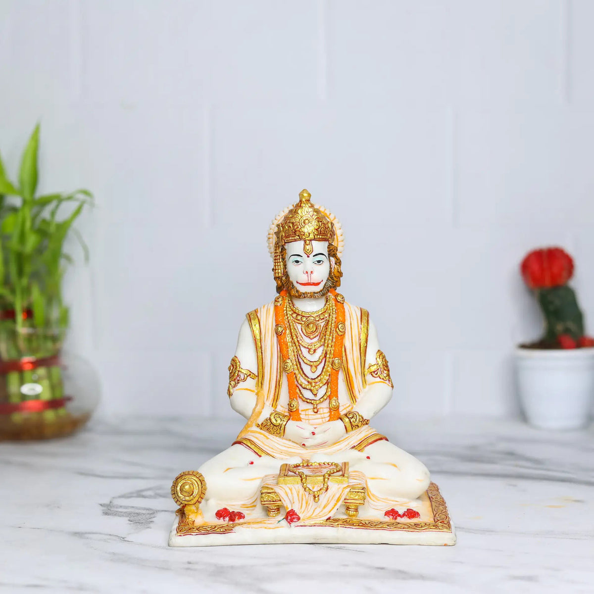 Aurance Lord Hanuman sitting statue in a meditative pose, reading a book with a gada, featuring gold and white details.