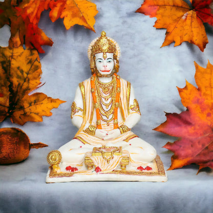 Aurance Lord Hanuman sitting statue in a meditative pose with a gada and book, featuring white and gold detailing.