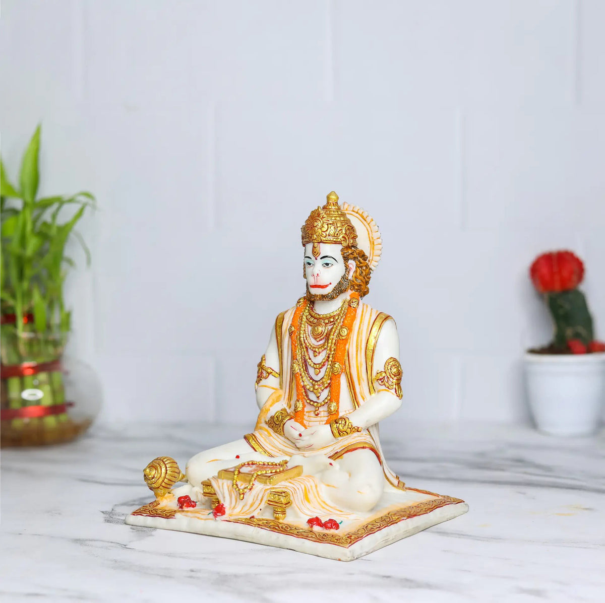 Aurance Lord Hanuman sitting statue in a meditative pose, reading a book with a gada, featuring gold and white detail.