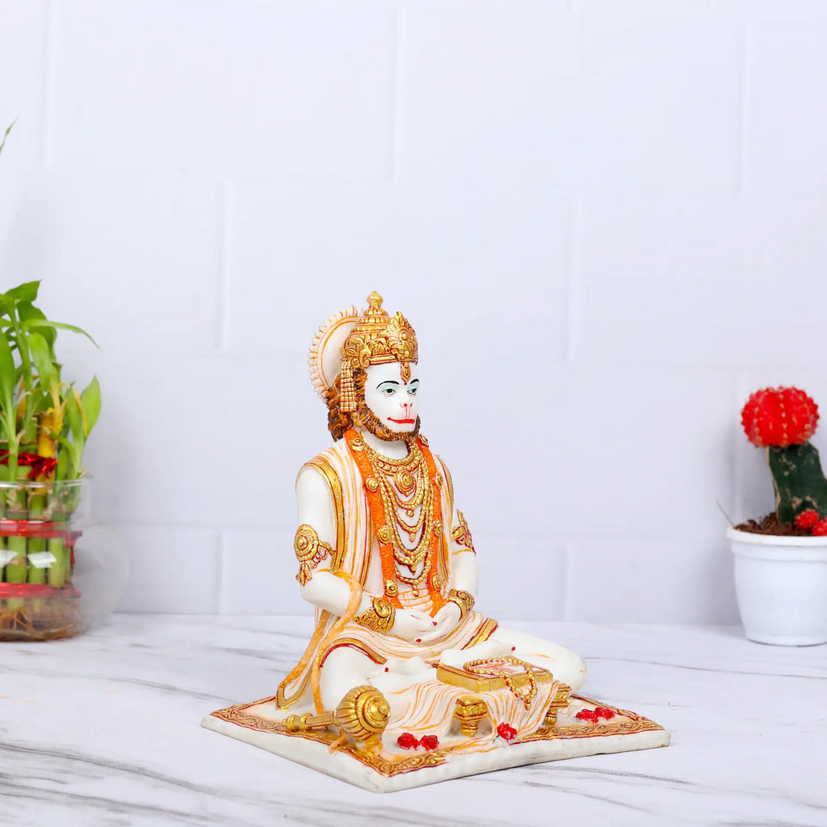Aurance Lord Hanuman sitting statue in a meditative pose, holding a gada and reading a book with gold accents.