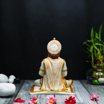 Aurance Lord Hanuman sitting statue seen from behind, featuring white and gold detailing, on a wooden surface.